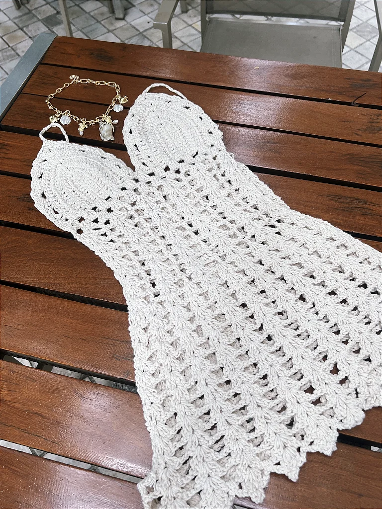 Vestido de crochê fotografado de forma amadora, sobre a mesa